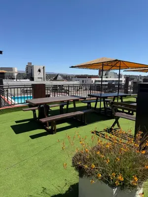two picnic tables with an umbrella on a roof at Departamento en el Centro Completo, Cochera, Pile, Pile Clim in Villa Carlos Paz