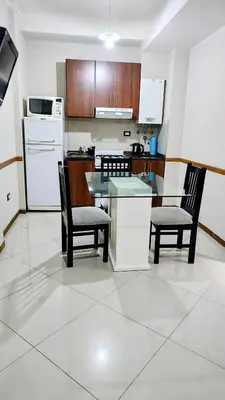 a kitchen with a table and two chairs and a counter at Departamento en el Centro Completo, Cochera, Pile, Pile Clim in Villa Carlos Paz