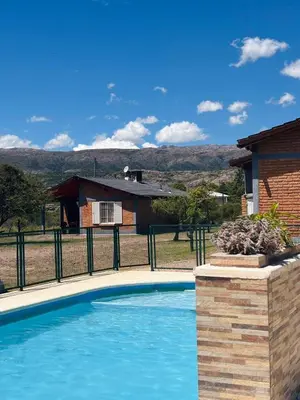 a swimming pool in front of a house at Complejo de cabañas El Nido in Mina Clavero