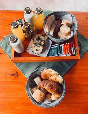 two trays filled with different types of bread and orange juice at Complejo de cabañas El Nido in Mina Clavero