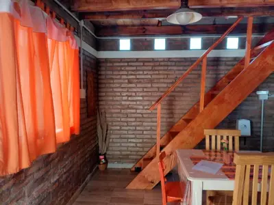 a room with a staircase with orange curtains and a table at Cabañas El Nirvana Villa Quillinzo in Villa Quillinzo