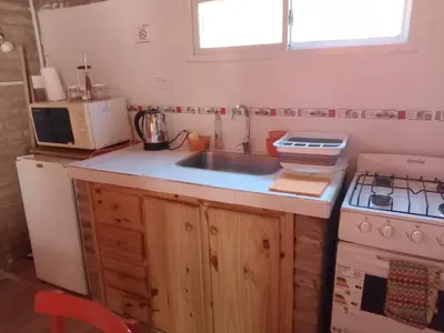 a kitchen with a sink and a stove and a microwave at Cabañas El Nirvana Villa Quillinzo in Villa Quillinzo