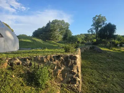 a stone wall in a field next to a building at Domo Bike in Villa Ciudad de America
