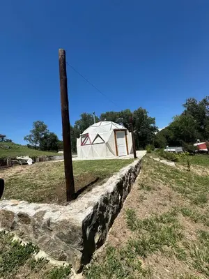 a tent in a field next to a stone wall at Domo Bike in Villa Ciudad de America