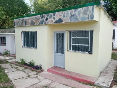a small white house with a stone wall at Las Vertientes in Tanti
