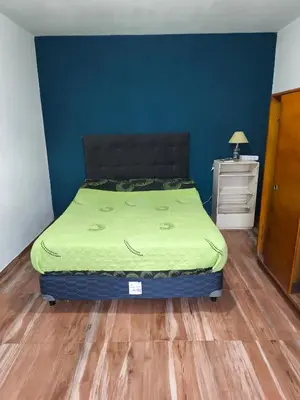 a bedroom with a bed with a green blanket on it at Casa El Buen Descanso Cura Brochero in Villa Cura Brochero