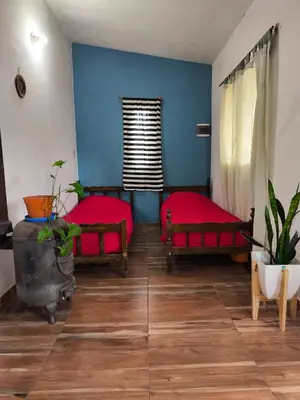 a room with two beds and a blue wall at Casa El Buen Descanso Cura Brochero in Villa Cura Brochero