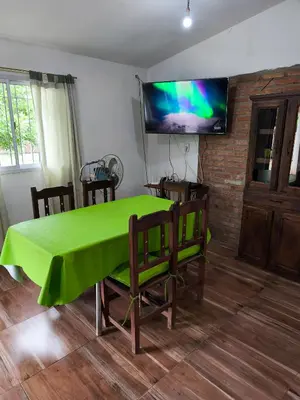 a green table with chairs and a television on a wall at Casa El Buen Descanso Cura Brochero in Villa Cura Brochero