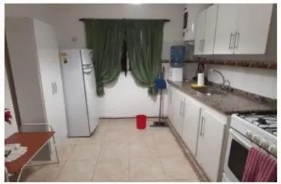 a kitchen with a refrigerator and a window with green curtains at El Tito Alojamiento in San Roque