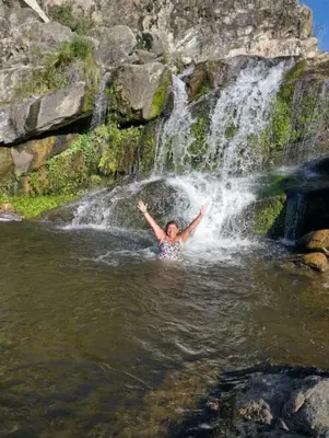 a man in the water in front of a waterfall at Las huertitas de Milele