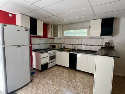 a kitchen with white appliances and red and white cabinets at Casa El Trapiche Lo Altos in Trapiche