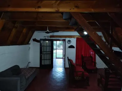 an attic room with a couch and chairs and a door at Cabaña A Mí Manera in Villa Carlos Paz
