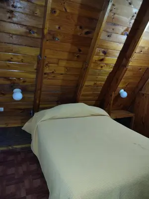a bedroom with a bed in a room with wooden walls at Cabaña A Mí Manera in Villa Carlos Paz