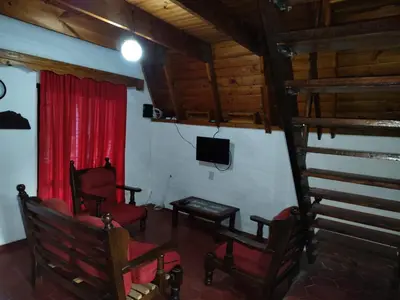 a living room with red chairs and a television at Cabaña A Mí Manera in Villa Carlos Paz