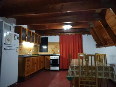 a kitchen with a table and a white refrigerator at Cabaña A Mí Manera in Villa Carlos Paz