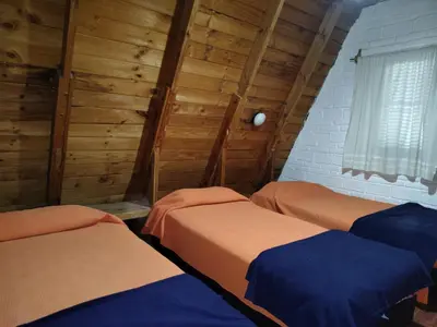 three beds in a room with wooden walls at Cabaña A Mí Manera in Villa Carlos Paz