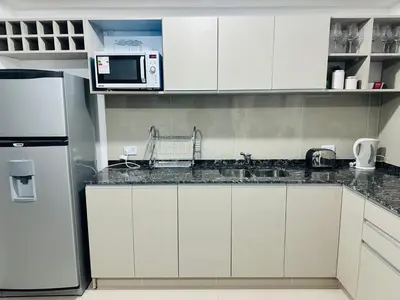 a kitchen with white cabinets and a microwave at Veneto village depto in Villa Parque Siquiman