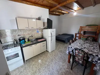 a kitchen with a refrigerator and a table with a tableablish at Monoambientes Pitu! in Villa Cura Brochero