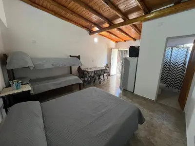 a bedroom with a bed and a kitchen with a table at Monoambientes Pitu! in Villa Cura Brochero