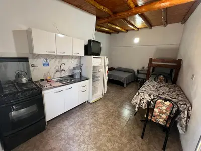a kitchen with white cabinets and a table and a stove at Monoambientes Pitu! in Villa Cura Brochero