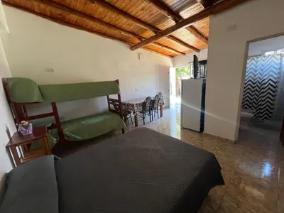 a living room with a bed and a refrigerator at Monoambientes Pitu! in Villa Cura Brochero