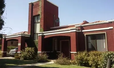 a red brick house with a car parked in front of it at La Morada in Mina Clavero