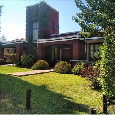 a red brick house with a grass yard at La Morada in Mina Clavero