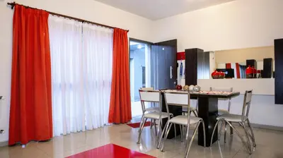 a dining room with red curtains and a table with chairs at Torre Myng in Villa Carlos Paz