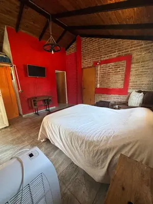 a bedroom with a white bed and a red wall at Miraflores in Santa Rosa de Calamuchita