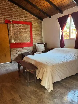 a bedroom with a large bed and a brick wall at Miraflores in Santa Rosa de Calamuchita