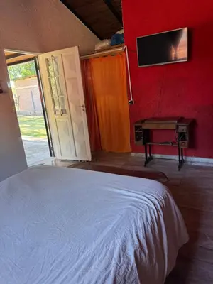 a bedroom with a bed and a tv on a wall at Miraflores in Santa Rosa de Calamuchita