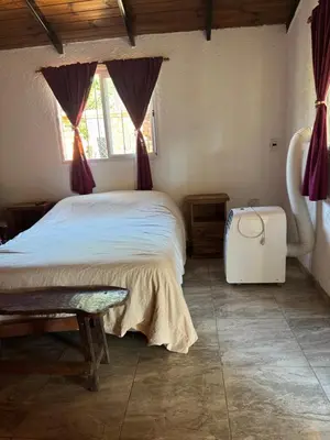 a bedroom with a bed and a window and a suitcase at Miraflores in Santa Rosa de Calamuchita