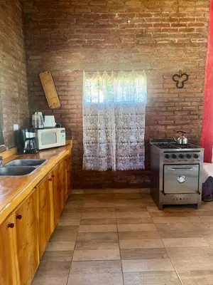 a kitchen with a stove and a sink and a microwave at Miraflores in Santa Rosa de Calamuchita