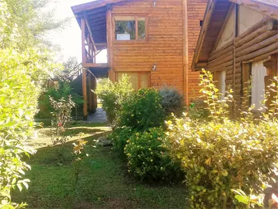 a wooden house with a garden in front of it at Ensueño Cabañas in Los Reartes