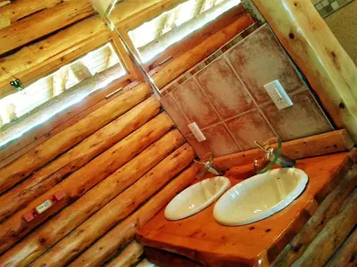 a bathroom with two sinks in a wooden wall at Ensueño Cabañas in Los Reartes