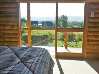 a bedroom with a large window with a bed in front at Ensueño Cabañas in Los Reartes