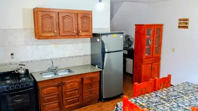 a kitchen with a stainless steel refrigerator and wooden cabinets at Casa, Rio y Familia Mina Clavero in Mina Clavero
