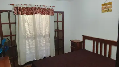 a bedroom with a bed and a window with curtains at Casa, Rio y Familia Mina Clavero in Mina Clavero