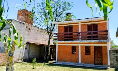 an old brick house with a tree in the yard at Casa, Rio y Familia Mina Clavero in Mina Clavero