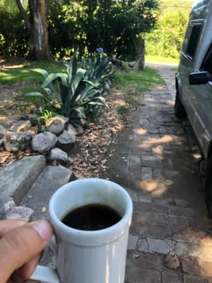 a person holding a cup of coffee in their hand at Kuku hostel in Las Rabonas