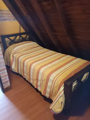 a bed with a striped blanket in a room at Cabaña Buena Vista Los Reartes in Los Reartes