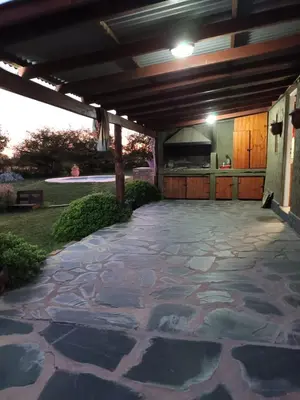 an outdoor patio with a stone floor and a stove at Cabaña Buena Vista Los Reartes in Los Reartes