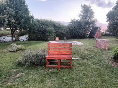a red chair sitting in the grass in a yard at Cabaña Buena Vista Los Reartes in Los Reartes