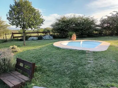 a small swimming pool in a yard with a bench at Cabaña Buena Vista Los Reartes in Los Reartes