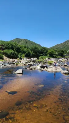 a group of people standing on the rocks in a river at Apart Playas de Oro in Villa Carlos Paz