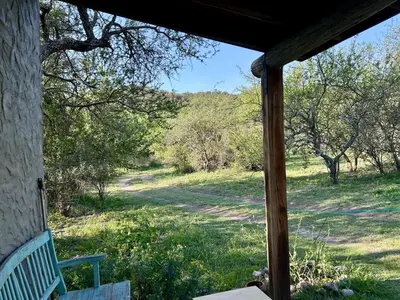a porch with a bench and a field with trees at Iris,Tiny house en Las Calles, Traslasierra in Las Calles
