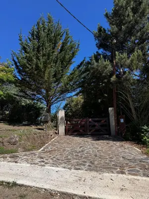 a wooden gate with a tree in the background at La Morondanga in Villa Yacanto