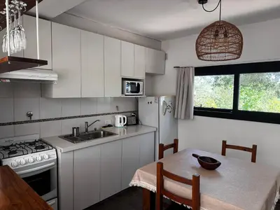 a kitchen with white cabinets and a table and a sink at La Morondanga in Villa Yacanto
