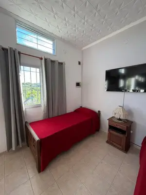a bedroom with a red bed and a television at Complejo turistico Alto del Valle in Villa Carlos Paz