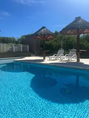 a swimming pool with two chairs and two umbrellas at Complejo turistico Alto del Valle in Villa Carlos Paz